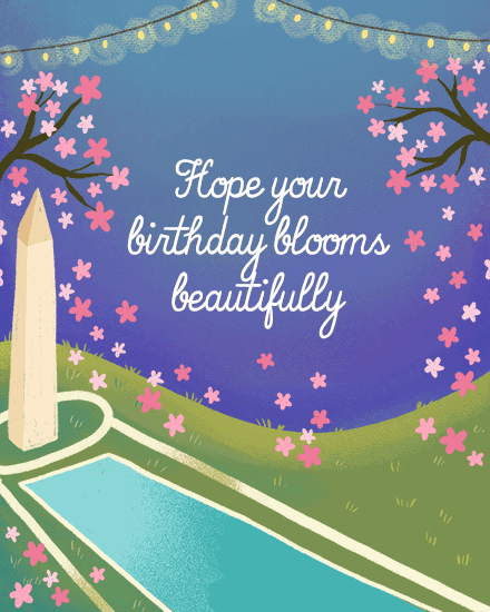 Twilight garden scene with pink blossoms, string lights, monument, reflecting pool, and cursive birthday message