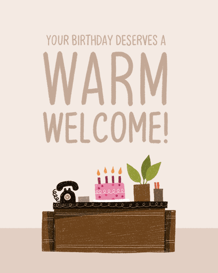 Hand-lettered birthday message above reception desk with phone, cake candles, and potted plant
