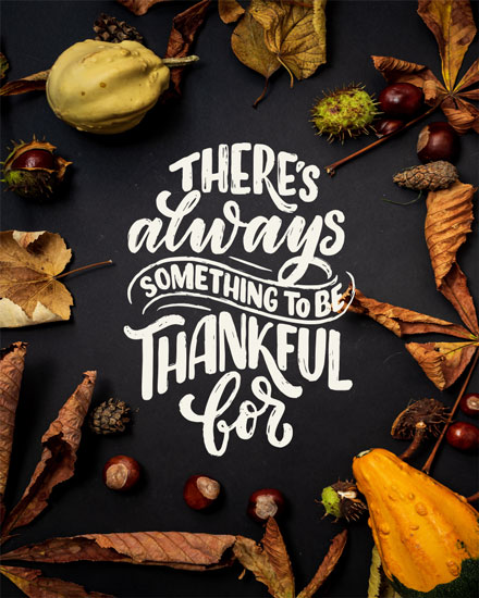 Autumn leaves, gourds, and chestnuts around 'Always Thankful' message on dark background.