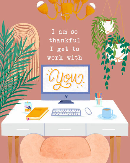 Office desk with computer, plants, and gratitude message on screen.